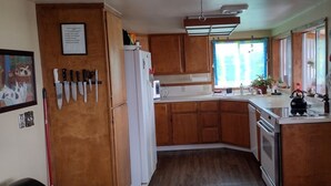 A compact kitchen with wooden cabinets, a white refrigerator, and a kettle on the counter.