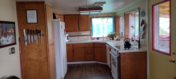 A compact kitchen with wooden cabinets, a white refrigerator, and a kettle on the counter.