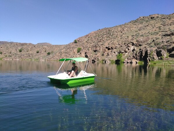 Un bote en un lago tranquilo con colinas rocosas al fondo.