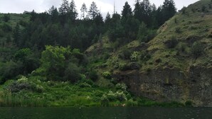 Un kayak verde sobre aguas tranquilas, con una ladera boscosa al fondo.