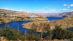 Un paisaje montañoso con un lago grande, un puente y un pueblo pequeño al fondo.