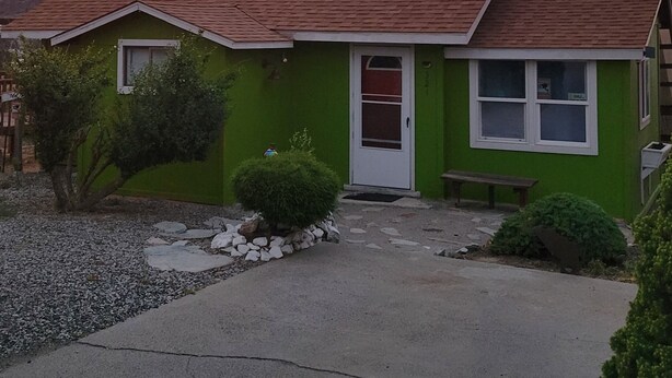 A single-story house with a red roof, green siding, and a front door.