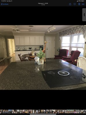 Enjoy cooking in this well-equipped kitchen with a stove, white cabinetry, and granite countertop.