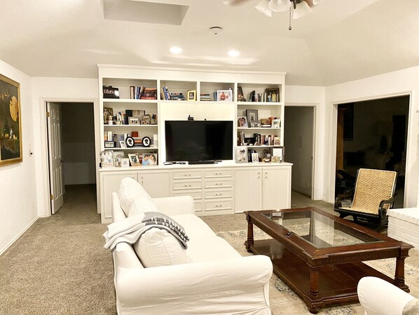 Relax in this cozy space with a comfortable sofa, flat-screen TV, and a collection of books and photographs.