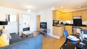A modern living room with a sofa, a glass coffee table, and a television. - Velvet 1-bedroom Apartment The Clockhouse, Hoddesdon (Hoddesdon)