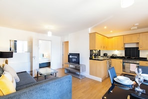 Una sala de estar moderna con un sofá, una mesa de centro de vidrio y un televisor.
