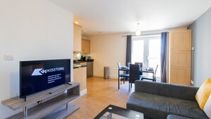A modern living room with a flat-screen TV, a sofa, and a dining area with a table and chairs. - Velvet 1-bedroom Apartment The Clockhouse, Hoddesdon (Hoddesdon)