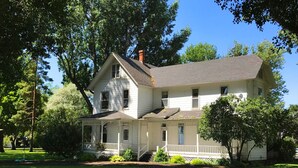 A two-story white house with a porch, surrounded by trees. - Granny's Farmhouse is a historic 1895 Victorian located on a working farm. (La Grande)