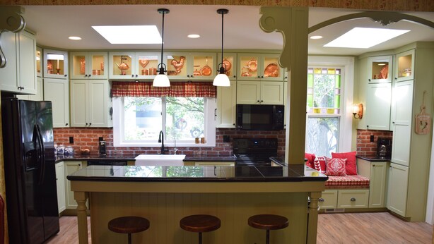 A kitchen with a central island, bar stools, and a seating area with a red cushion. - Granny's Farmhouse is a historic 1895 Victorian located on a working farm. (La Grande)