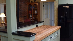 A kitchen with a central island, green cabinets, a brick wall, and a black refrigerator. - Granny's Farmhouse is a historic 1895 Victorian located on a working farm. (La Grande)