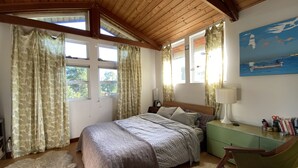 Un dormitorio con cama, mesita de noche, una silla y un cuadro en la pared.