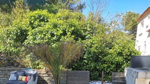Una terraza de madera con sillones reclinables y una pequeña zona de estar con cojines.