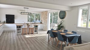 Una cocina moderna con una isla central, un área de comedor con mesa y sillas, y un ventanal que ofrece vistas al exterior.