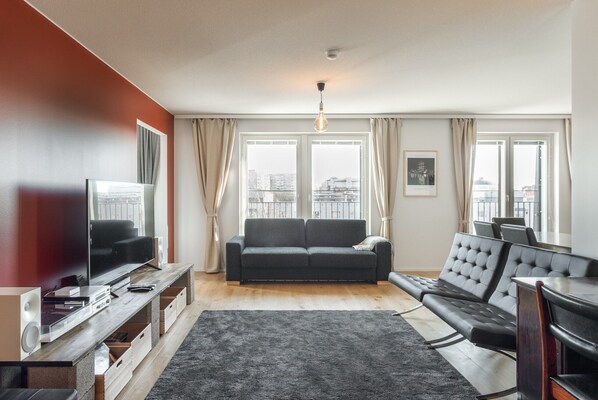A modern living room with a sofa, a TV, and a wooden entertainment unit.
