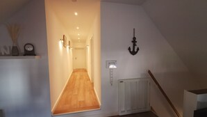 Un couloir doté d’un plancher en bois, d’un radiateur blanc et d’un luminaire fixé au mur.