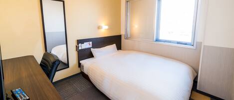 A hotel room with a bed, a desk, a chair, a mirror, and a window.