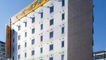 A modern hotel with a white facade and a yellow signboard.