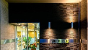 A hotel entrance with a modern design, featuring a glass door, a sign reading "SUPER HOTEL", and a textured wall. - Super Hotel Natural Hot Springs Fuji (Fuji)