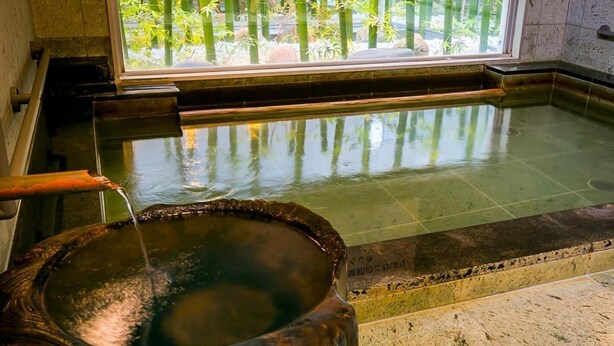 A traditional Japanese onsen with a wooden basin and a stone-lined pool. - Super Hotel Natural Hot Springs Fuji (Fuji)