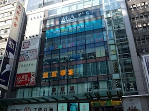 A modern building with multiple floors, glass facade, and various commercial signs.