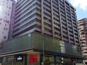 A multi-story building with a modern architectural design, featuring a glass facade and multiple balconies.