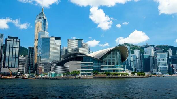 A modern city skyline with prominent skyscrapers and a distinctive curved building near a waterfront. - Elog Inn at National Court (Kowloon)