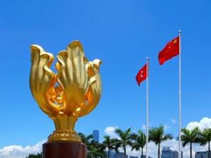A golden lotus sculpture with two red flags in the background. - Elog Inn at National Court (Kowloon)