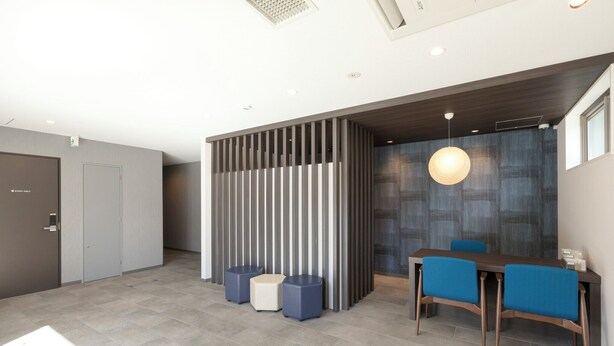A modern hotel lobby with a reception desk, seating area, and a decorative partition. - M's Hotel Kyoto Station Taruya (Kyoto)