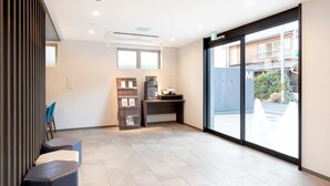 A modern waiting area with a reception desk, seating, and a large window offering a view of the outside. - M's Hotel Kyoto Station Taruya (Kyoto)