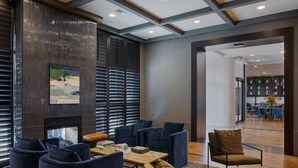 Un espace détente moderne avec des canapés bleu foncé, une table basse en bois et un tapis à motifs.