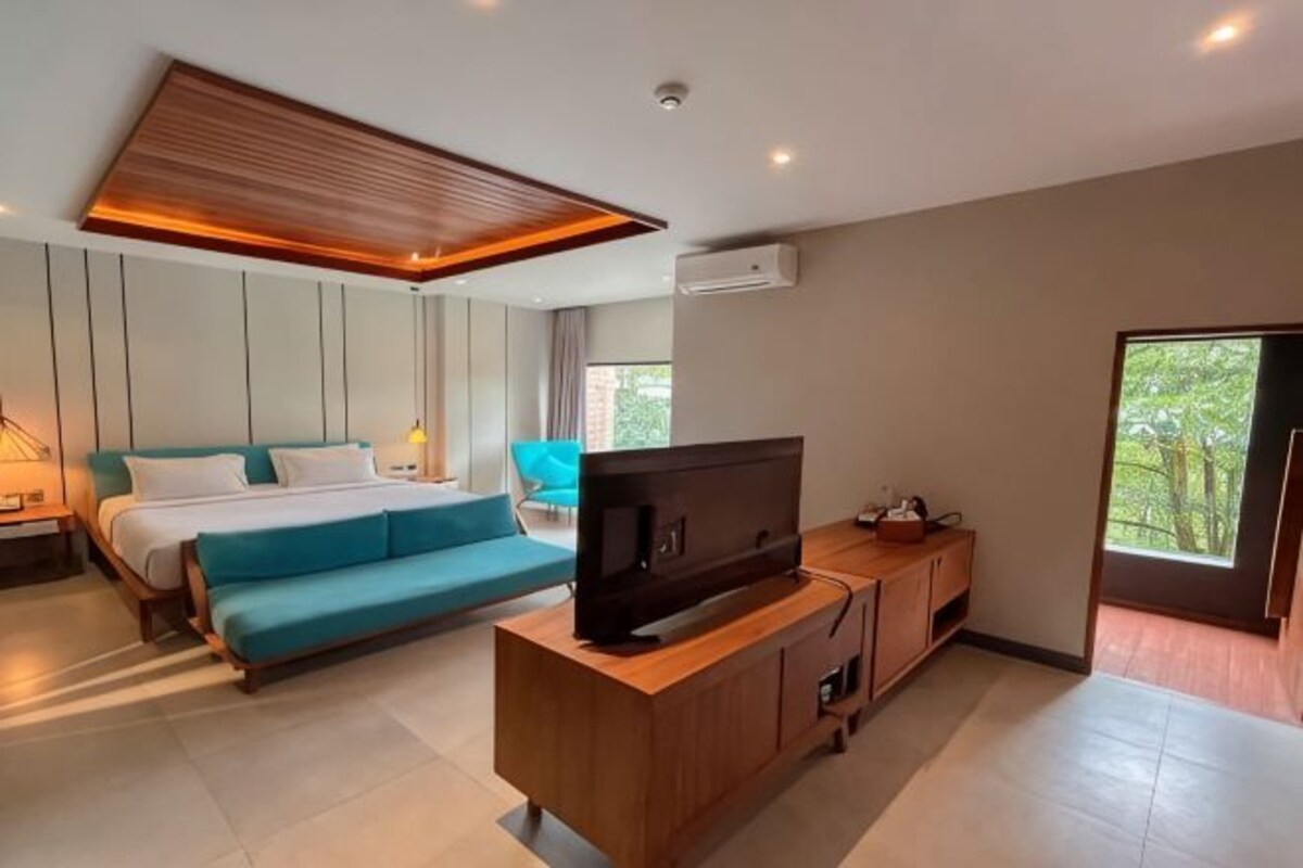Una habitación de hotel moderna con cama, sofá, televisión y un mueble de madera.