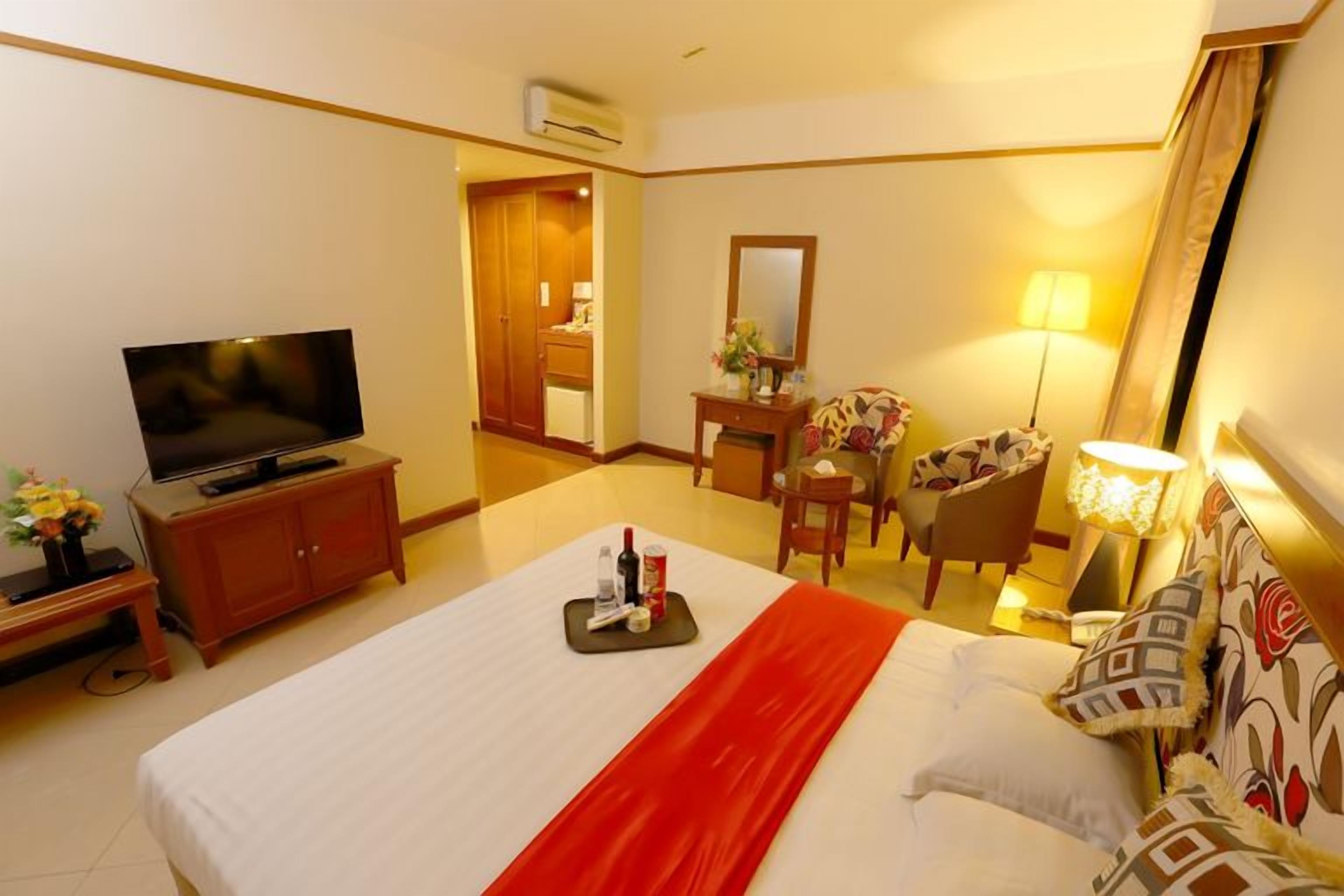 A hotel room with a bed, a television, a desk, a chair, and a lamp.