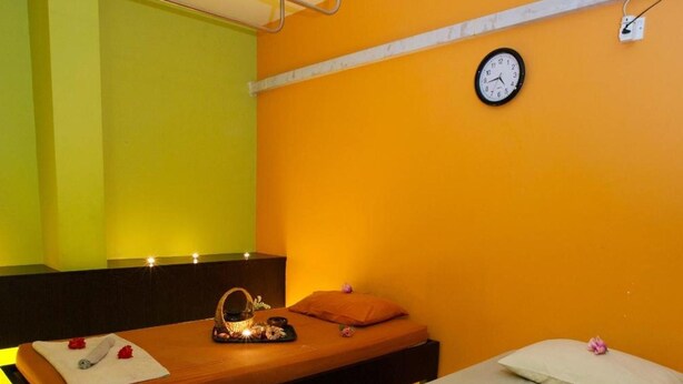 Una stanza con un letto, un lettino per massaggi, una sveglia e una parete orologio.