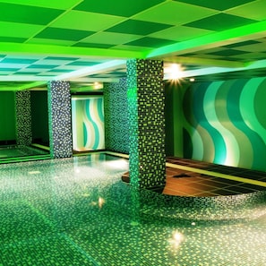 A modern interior with green-tiled floors, a wavy wall design, and a tiled column structure. - Hotel Maximillian (Karimun)