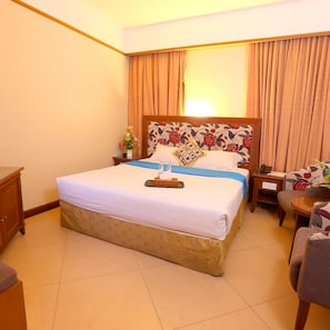 A hotel room with a bed, a nightstand, a chair, and a desk. - Hotel Maximillian (Karimun)