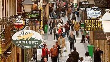 A bustling street with people walking, shops, and signs in a European city.