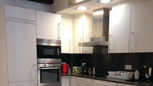 A modern kitchen with white cabinets, stainless steel appliances, and a red carpet. - Spacious, Central and Authentic Family Apartment (Donostia)