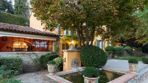 A courtyard with a fountain, potted plants, and a building with a tiled roof and windows. - La Bastide de Barbeiranne Maxi 14 persons (Pignans)
