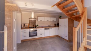 A modern kitchen with white cabinets, a built-in oven, and a wooden staircase. - Vacation in Saxon Switzerland (Pirna OT. Graupa)