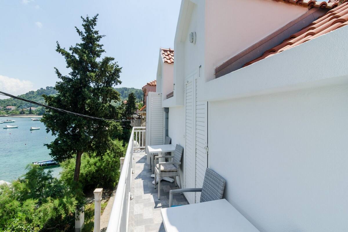 A balcony with white furniture overlooking a body of water with boats.