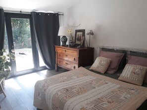 Une chambre à coucher avec un lit, une commode, une lampe et une fenêtre avec des rideaux.