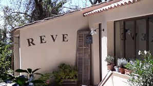 A building with the word "REVE" on the wall, a wooden door, and potted plants outside. - Charming and quiet cottage (Aix-en-Provence)