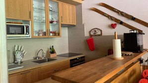 A modern kitchen with wooden cabinets, a microwave, a sink, and a coffee machine. - Spacious 6-person apt. with balcony and direct piste access (Pra-Loup)