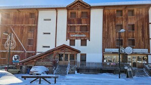 A building with a wooden facade, a sign for 'Le Chamois', and a 'SNACK BAR' sign. - Spacious 6-person apt. with balcony and direct piste access (Pra-Loup)