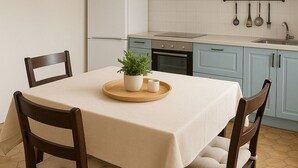 A dining area with a table set for two, a hanging light fixture, and light blue cabinets in the background.