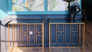 Une pièce agrémentée d’une grande fresque murale aux motifs tropicaux, d’une console moderne et d’une sculpture décorative.