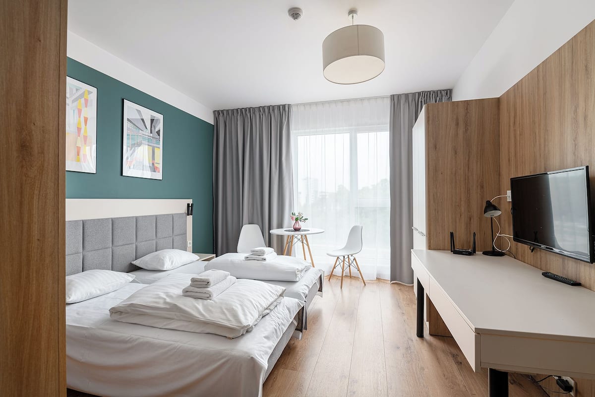 A hotel room with a bed, a desk, a TV, and a small table with chairs.