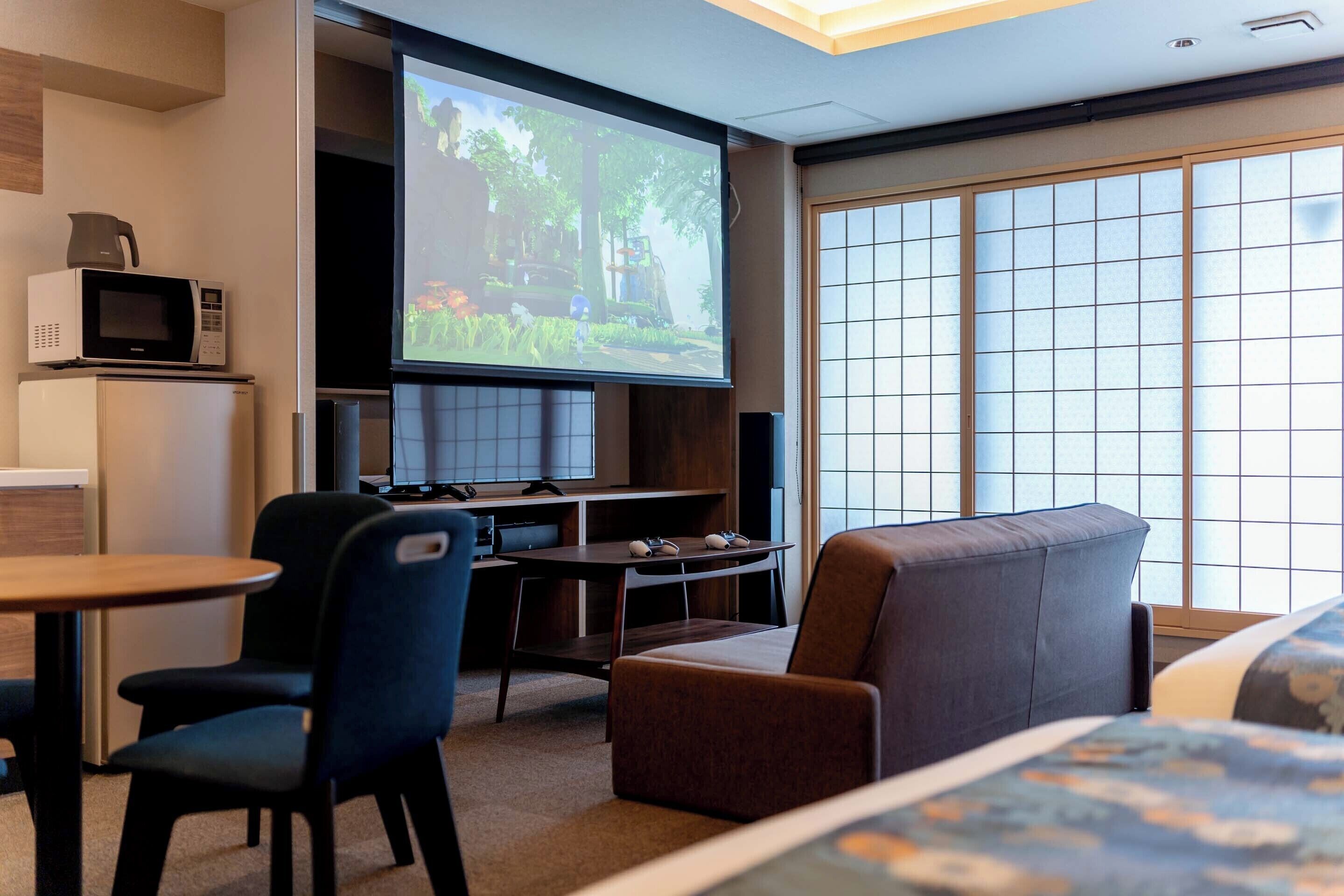 A hotel room with a television, a microwave, a small table, a sofa, and a bed.