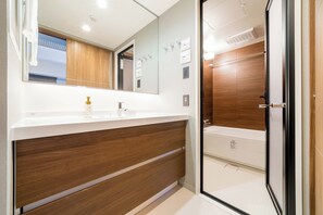 A modern bathroom with a wooden vanity, a large mirror, and a glass shower enclosure. - RESI STAY HOTEL SUN CHLORELLA　 (Kyoto)