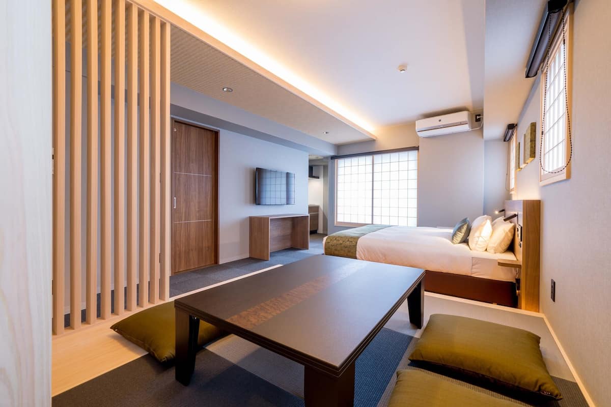 A modern hotel room with a bed, a desk, a TV, and a sliding door.